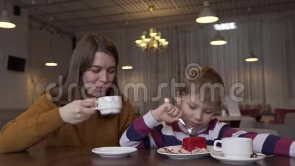 可爱的年轻妈妈喝着浓咖啡和她可爱的小儿子说话视频的预览图