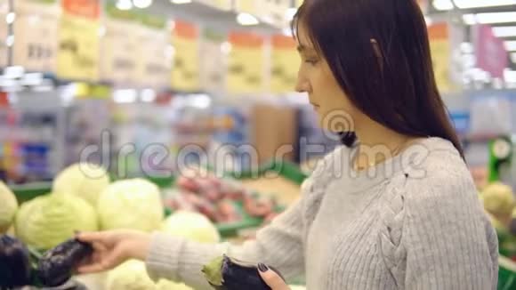 超市蔬菜部的年轻女子选茄子视频的预览图