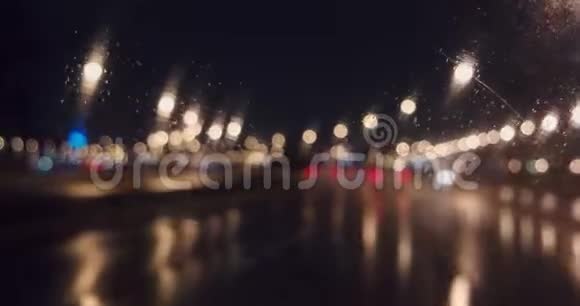 夜间高速公路的模糊灯光通过挡风玻璃和工作雨刷视频的预览图