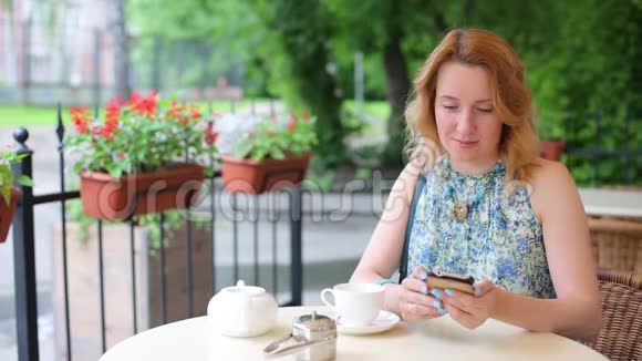 咖啡馆里的女人手里拿着电话喝咖啡隆丁卡一名女子在与电话提供午餐女人穿着视频的预览图