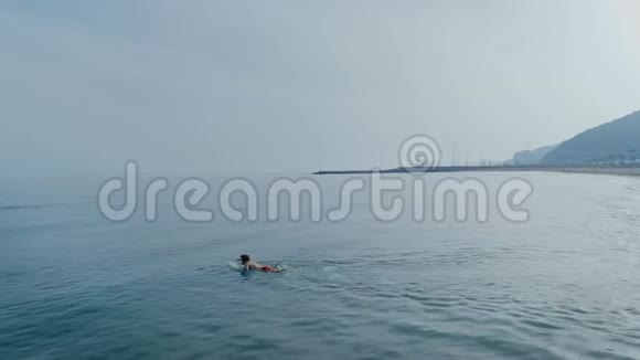 冲浪者在冲浪板上游泳寻找海浪视频的预览图