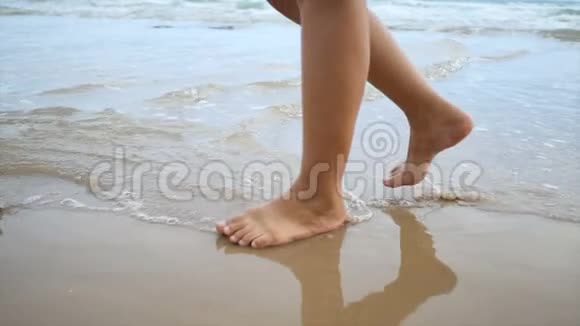慢动作女子双脚在沙滩上漫步与自然海浪海岸为暑假概念视频的预览图