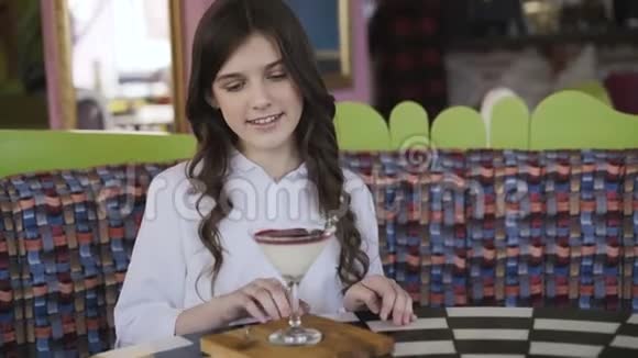 快乐的女孩带着微笑在咖啡馆的桌子上旋转鸡尾酒果冻4K视频的预览图