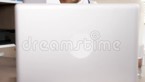 近距离看医生桌桌上有笔记本电脑在数字平板电脑上浏览纸质笔记本电脑视频的预览图