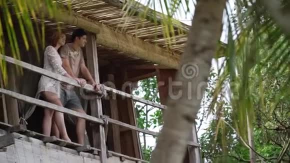 阳光普照的丛林别墅露台上的男人和女人视频的预览图