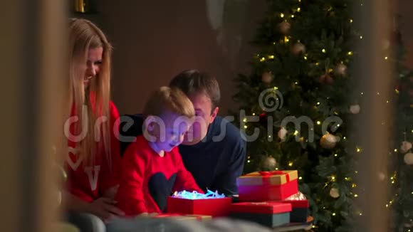 幸福家庭的肖像在晚上打开圣诞礼物盒假期概念惊喜快乐视频的预览图