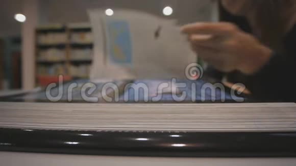 年轻的高加索女人在图书馆翻阅一本插图的书低角度拍摄视频的预览图
