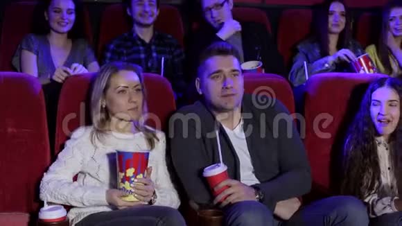 一群年轻人在电影院里与爆米花和可乐的合影视频的预览图