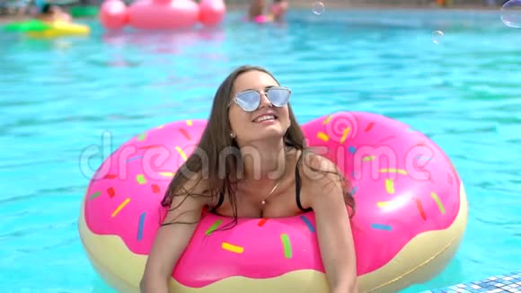 夏天美丽的年轻女子比基尼女郎在游泳池度假夏日派对上享受着洒在甜甜圈里的乐趣视频的预览图