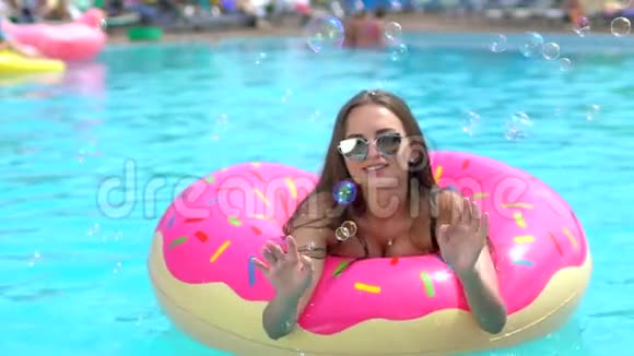 夏天美丽的年轻女子比基尼女孩哈文在洒满甜甜圈的乐趣在游泳池假期夏天夏天视频的预览图