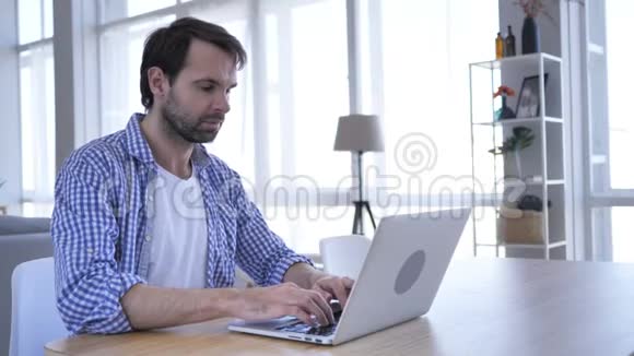 穿便便装的胡须男在笔记本电脑上思考和工作视频的预览图