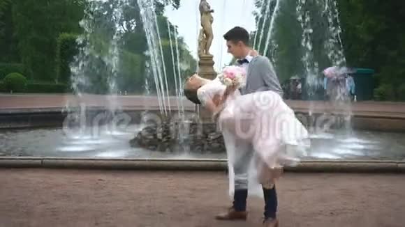新郎把新娘抱在怀里亲吻喷泉的背景视频的预览图