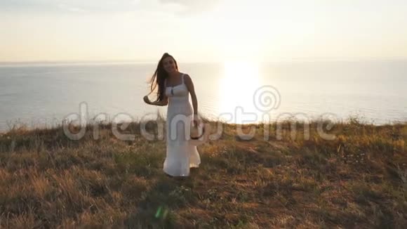 一位身穿白色连衣裙的长发黑发女子在悬崖上为照相机摆姿势视频的预览图