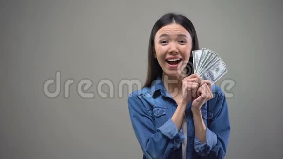 令人兴奋的亚洲女人在镜头上展示美元钞票彩票中奖者财富视频的预览图