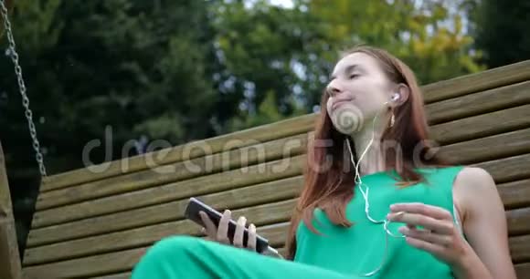 情感舞蹈的女孩听音乐时带着耳机在秋千上视频的预览图