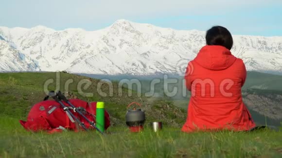 旅行者的女人坐在山上在煤气炉上一个塞尼克女人看着雪山视频的预览图
