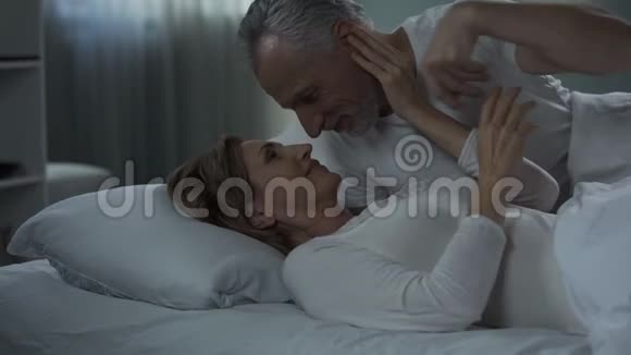 一对年老的夫妇躺在床上互相抚摸男人亲吻女人的手爱视频的预览图