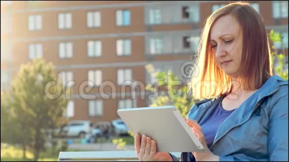 坐在城市长凳上用平板电脑的女人视频的预览图