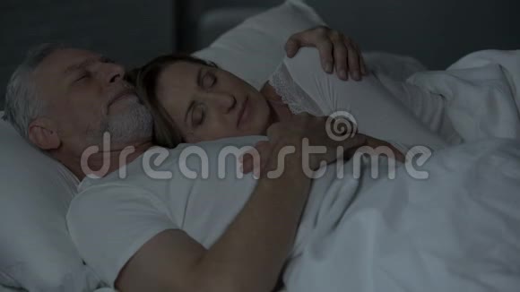 老夫妇睡在床上女士躺在男性的胸部男人抱着她的手臂视频的预览图