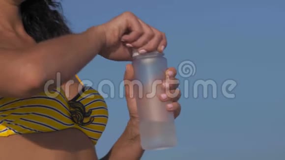 比基尼的贴身女人在海滩上打开瓶子和饮料视频的预览图