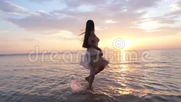 在阳光下的年轻女子在岸边的水里旋转视频的预览图