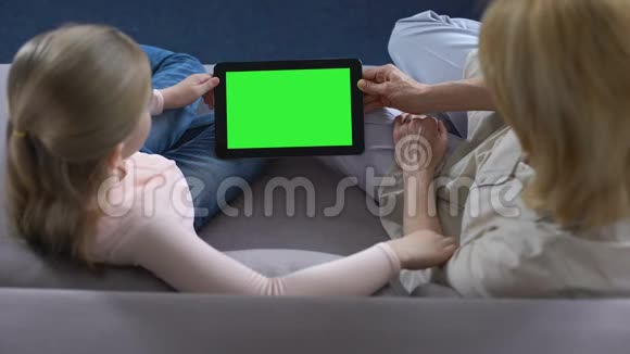 祖母和小祖母手持绿色屏幕平板电脑应用程序视频的预览图
