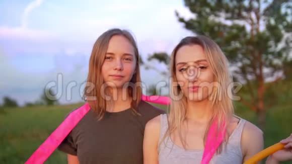 两名年轻女子体操运动员在夏季日落时带着体操器械在山上的肖像视频的预览图
