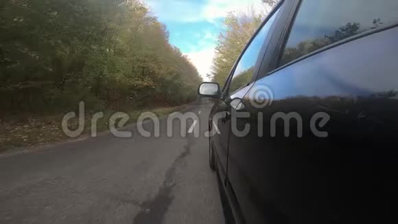 汽车轮胎在阳光明媚的秋天行驶在明亮的秋林中旋转视频的预览图