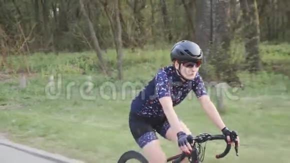 在公园里骑着自行车跟着女三项运动员的镜头侧视铁人三项训练理念慢动作视频的预览图