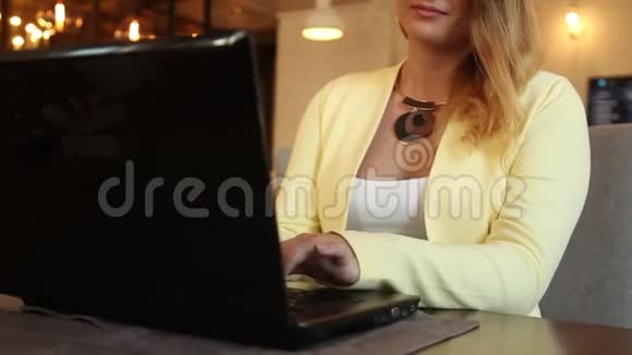 特写镜头漂亮的商务女性在一台移动电脑上打字坐在咖啡馆的桌子旁心情很好高清视频的预览图