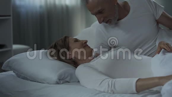 年长的男人和女人躺在床上抚摸着幸福的婚姻温柔的视频的预览图