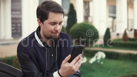 成年男子使用智能手机的视频通话坐在户外视频的预览图