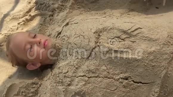 女孩在沙滩上挖沙子有乐趣和快乐的概念小可爱的女孩在玩海沙玩得开心视频的预览图