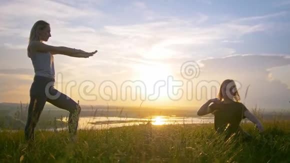两个年轻的女人在夏天日落时在山上热身视频的预览图