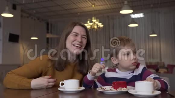 可爱的年轻母亲喝咖啡和她可爱的小儿子说话视频的预览图