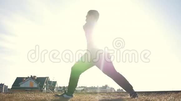 年轻男子跑酷特技运动员在训练前在太阳前做热身运动视频的预览图