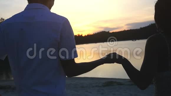 浪漫的情侣牵着手在令人惊叹的在海滩上散步慢动作1920x1080视频的预览图