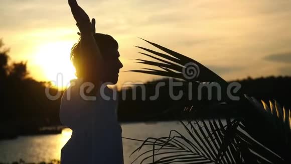 年轻的商人站在棕榈树旁边的热带海滩上缓慢地举起双手向空中移动自由概念视频的预览图