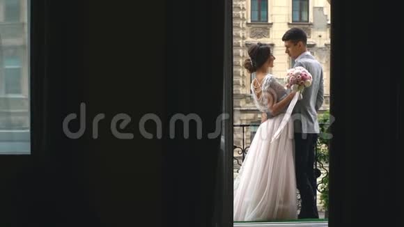 年轻夫妇爱上了新婚夫妇站在白色阳台上手牵手后景视频的预览图