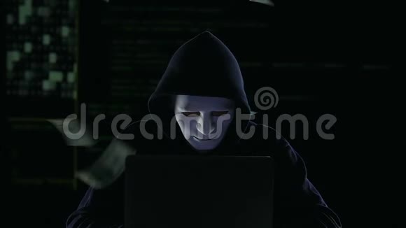 戴着面具的黑客在手提电脑上工作美元账单下降洗钱视频的预览图