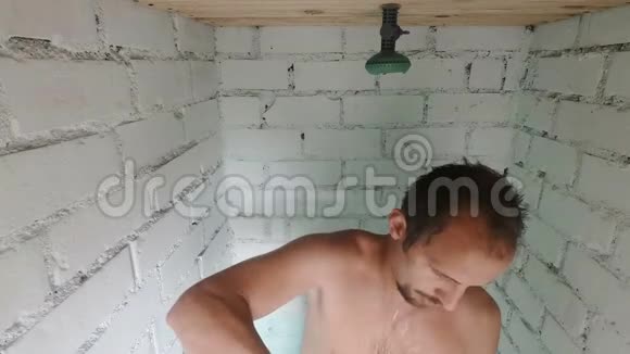 有胡子的滑稽男人在老式的砖砌浴室里洗个澡头上洗头视频的预览图