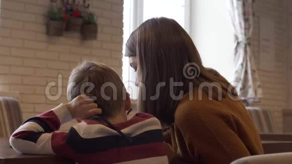 一对迷人的年轻母亲和儿子坐在餐桌旁视频的预览图