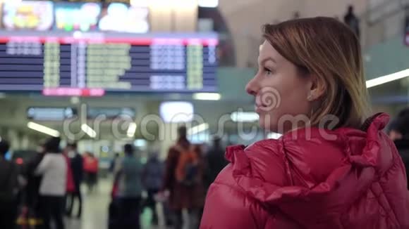 国际机场或火车站的美丽年轻旅游女孩靠近飞行信息板视频的预览图