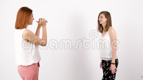 一位年轻女子正在一面白墙上拍摄另一幅视频的预览图