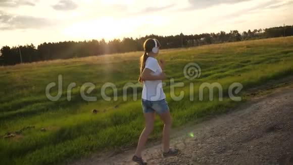 音乐耳机里的女孩沿着路跑做运动运动的漂亮女孩视频的预览图