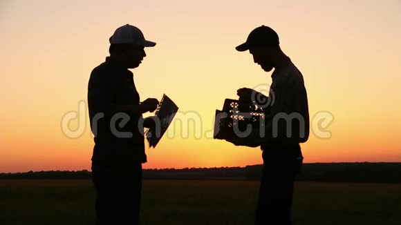 两个农民在日落时交谈看着夕阳上的葡萄侧视图视频的预览图