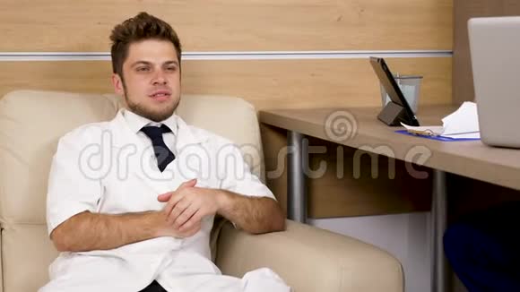坐在沙发上的年轻医生和他的同事谈话视频的预览图