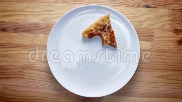 顶部拍摄时间流逝白色盘子上的披萨片正在被咬和完成同时站在木制桌面上室内视频的预览图