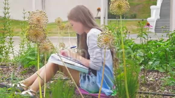 坐在花丛里的小女孩在公园里写笔记视频的预览图