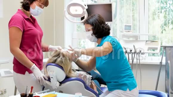 4k牙科医生与助理Trating病人坐在牙科椅上的录像视频的预览图